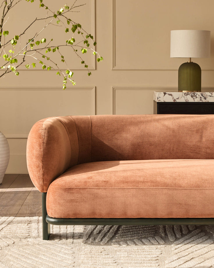 Florence 2-seater sofa in apricot fabric with dark wood base, shown in a styled living room setting.