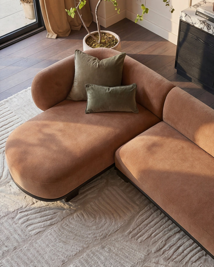 Florence left-hand-facing chaise sofa in apricot fabric with dark wood base, styled with sage green pillows in a modern living room.