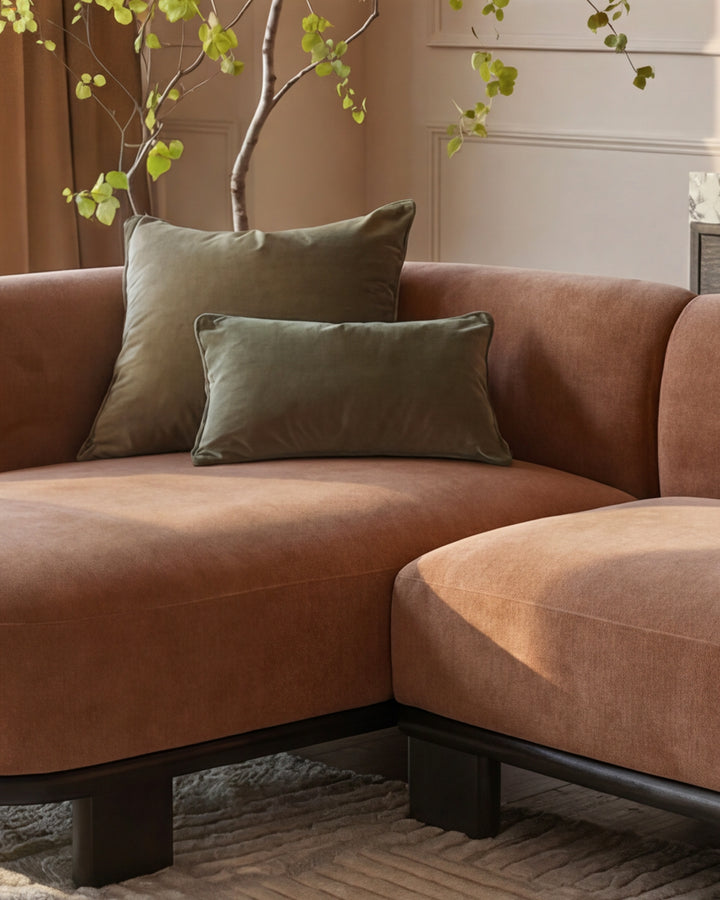 Florence left-hand-facing chaise sofa in apricot fabric with dark wood base, styled with green cushions and decorative branches.