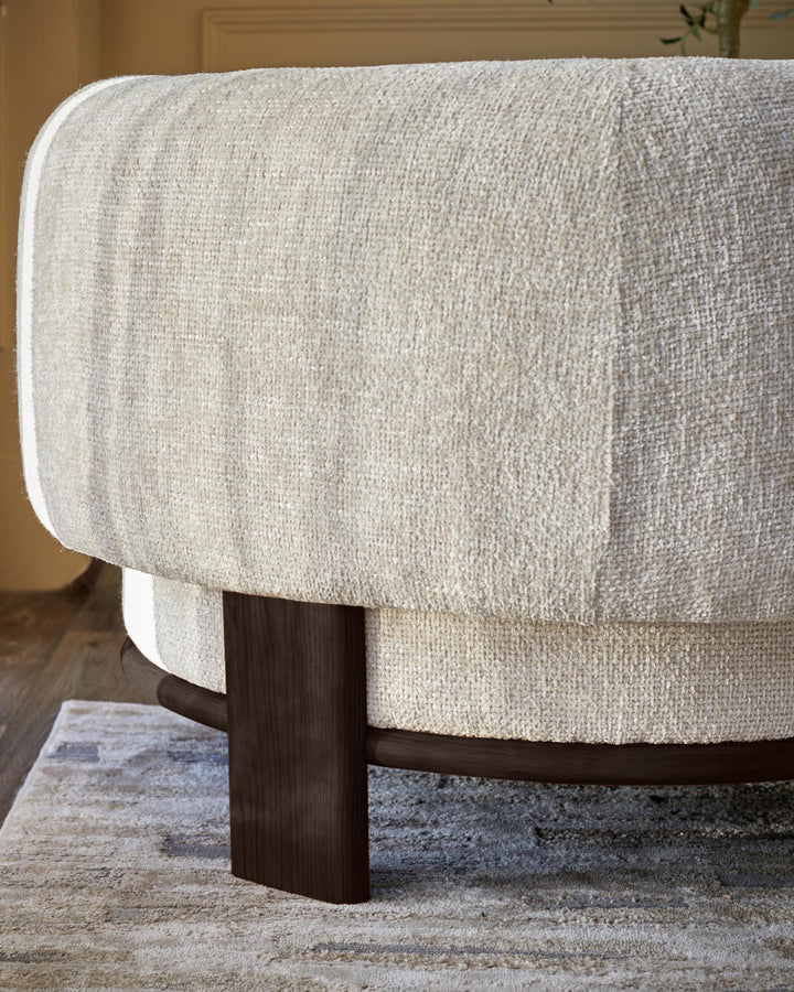Close-up of a neutral-toned, textured fabric armchair with dark wooden legs, showcasing its modern design.