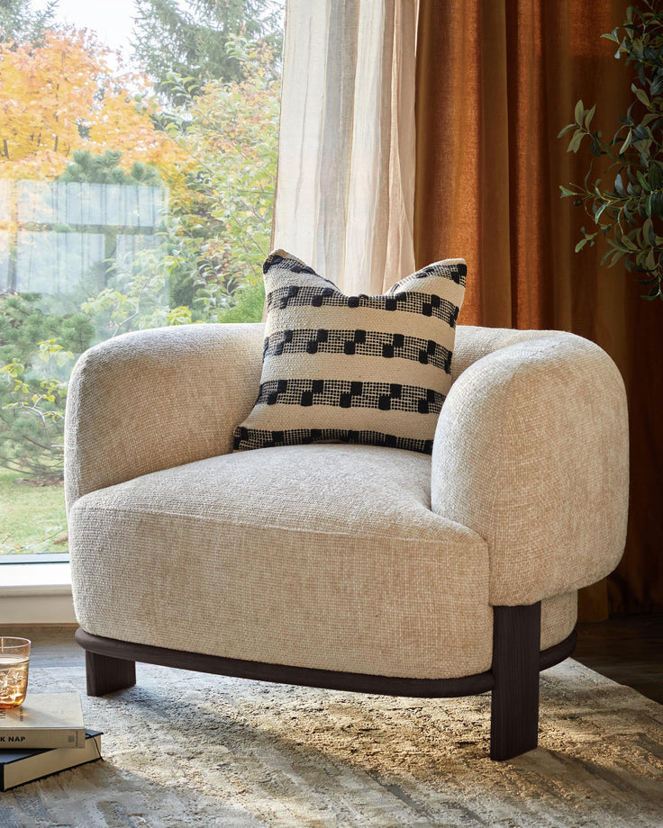 Beige armchair with patterned cushion. Modern design for a cosy living space.