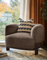 A cosy armchair with a geometric cushion, perfect for relaxing in a contemporary living space.