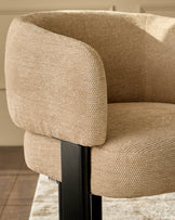 Florence dining chair in honey fabric, close-up detail showing textured weave and curved armrest with black wooden frame.