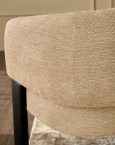 Florence dining chair in honey fabric, close-up of curved backrest showing textured weave and black wooden leg.