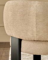 Close-up of Florence dining chair showing honey-colored woven fabric upholstery and black wooden leg detail.
