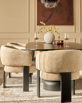 Florence dining chair in honey fabric, shown in a styled dining room setting with round black table and coordinating chair.