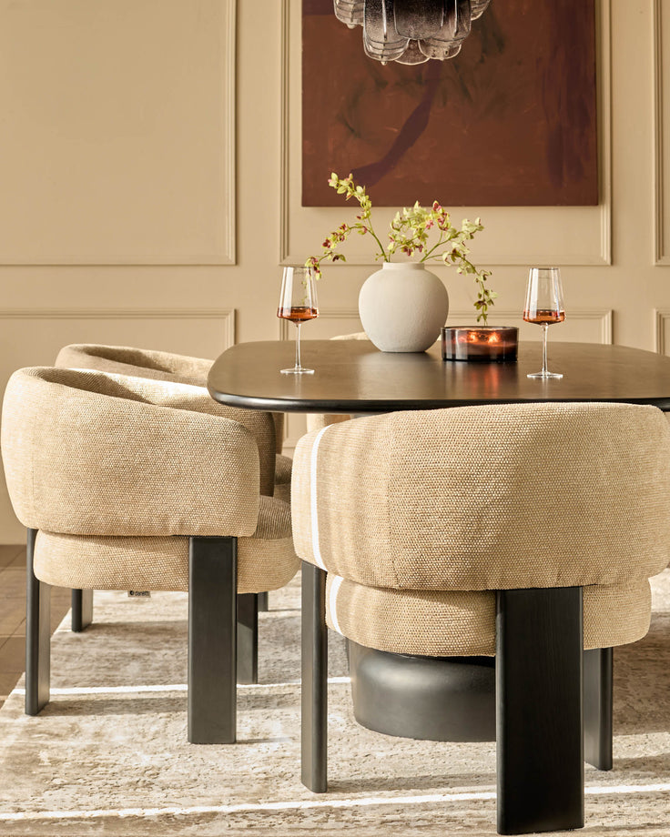 Florence dining chair in honey fabric, shown in a styled dining room setting with round black table and coordinating chair.