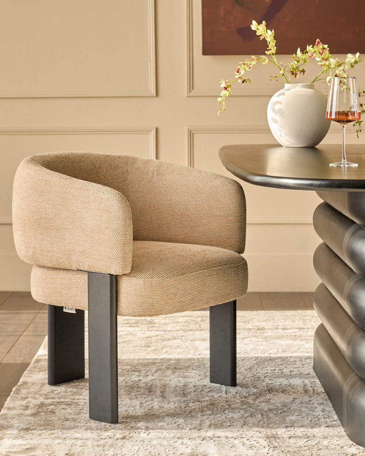 Florence dining chair in honey fabric with black metal legs, shown in a styled room setting beside a round table.