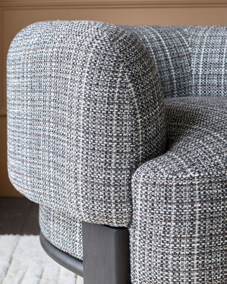 Florence armchair with dark wood frame and light gray woven fabric, shown in close-up detail of curved armrest.
