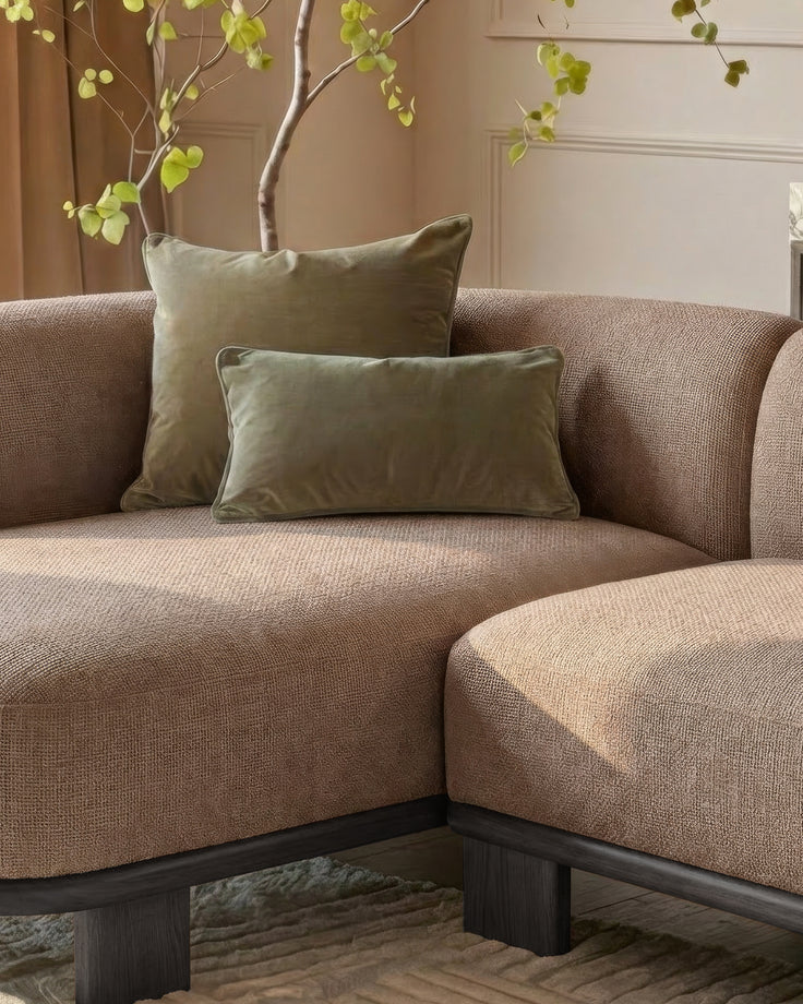 Florence left-hand facing chaise sofa in mocha fabric with dark wood base, styled with green pillows and decorative plant.