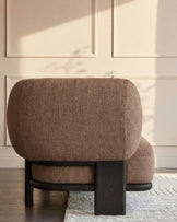 Mocha fabric corner sofa with dark wood frame, viewed from rear angle in bright sunlit room.
