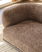 Mocha fabric curved armchair with rounded backrest and seat, metal base, angled side view on light wood flooring.