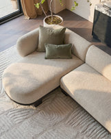 Florence left-hand chaise sofa in natural fabric with dark wood base, styled with olive green pillows in a modern living room.