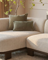 Florence left-hand-facing chaise sofa in natural fabric with dark wood base, styled with sage green pillows and decorative branch.