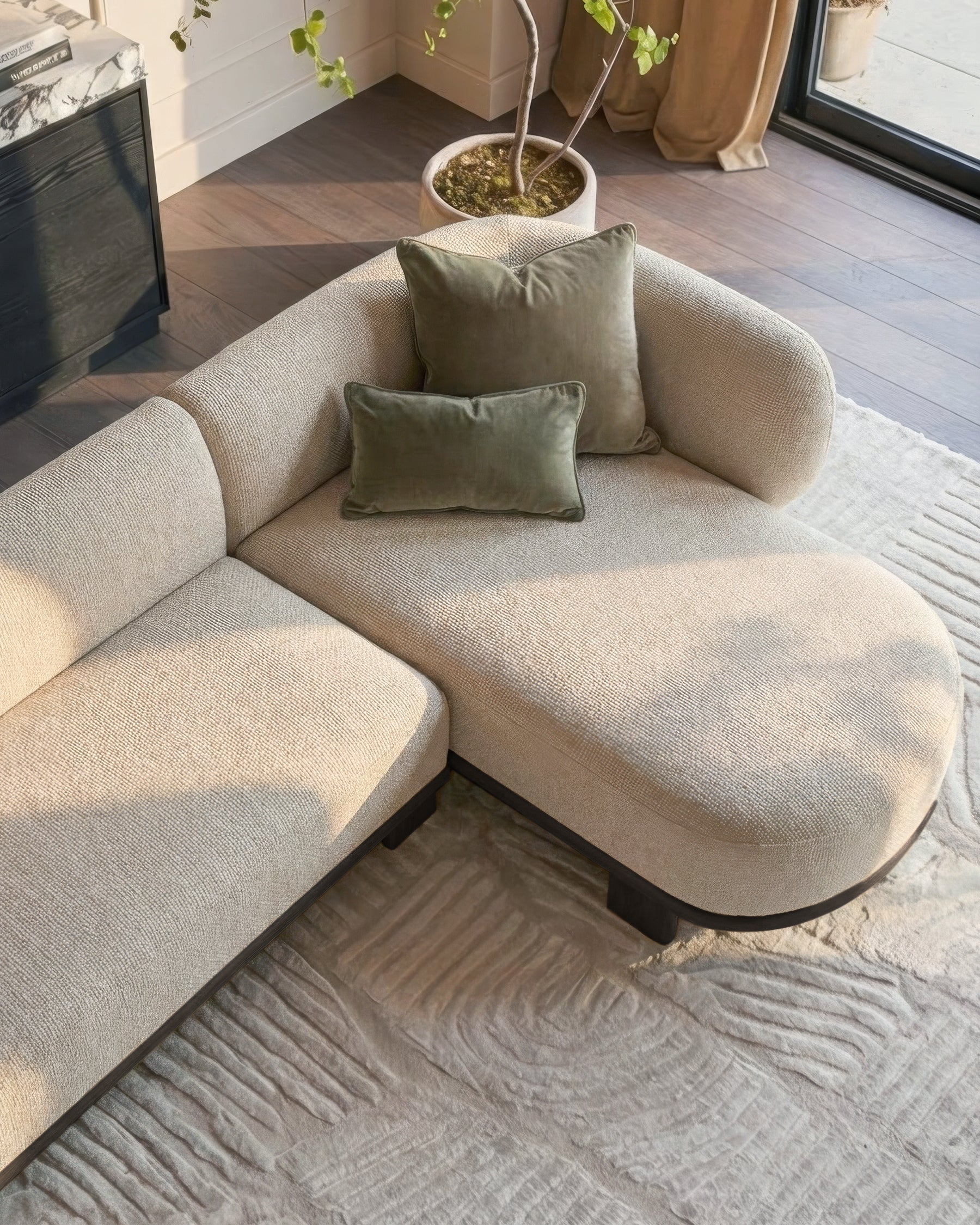Florence right-hand facing chaise sofa in natural fabric with dark wood legs, styled with green pillows in a bright living room.