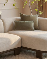 Florence right-hand facing chaise sofa in natural fabric with dark wood base, styled with olive pillows and decorative branch.