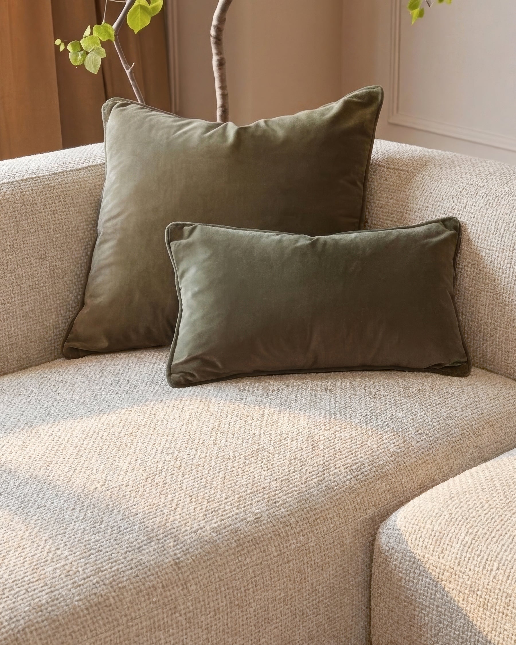 Florence left-hand chaise sofa in natural fabric with olive green pillows and dark wood legs, angled view.
