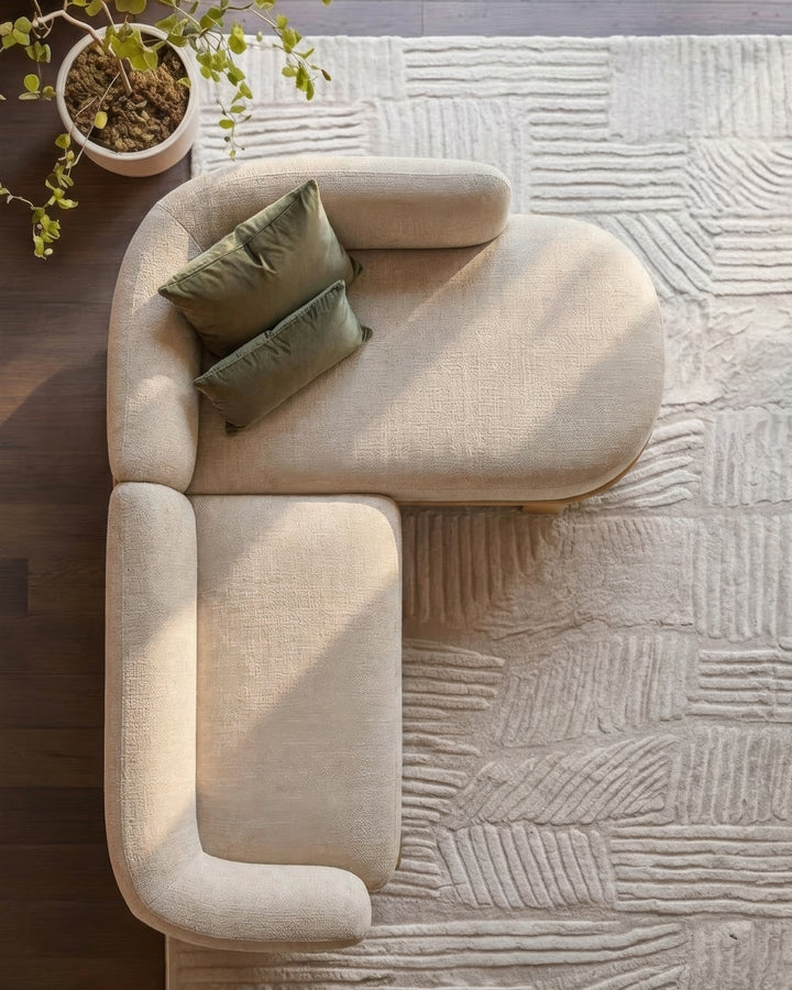 Florence right-hand-facing chaise sofa in natural fabric with light wood base, overhead view with olive pillows and potted plant.