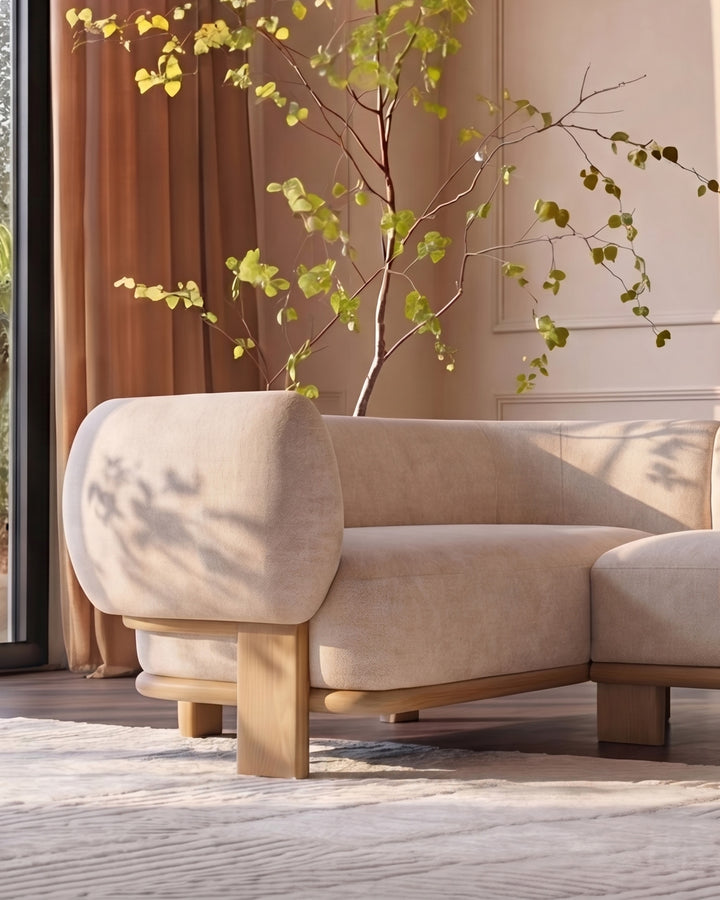 Florence left-hand-facing small corner sofa in natural fabric with light wood legs, positioned in a bright room with decorative branches.