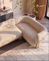 Florence right-hand-facing small corner sofa in natural fabric with light wood legs, displayed in a bright living room setting.