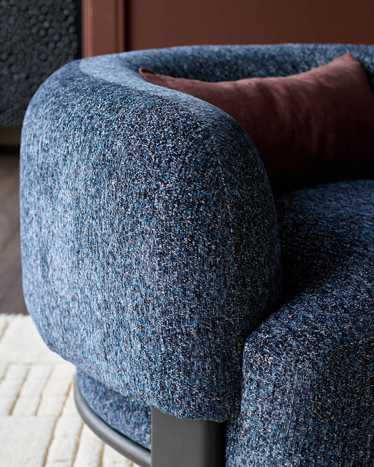 Florence armchair in navy weave fabric with curved arms and dark wood base, detail view.