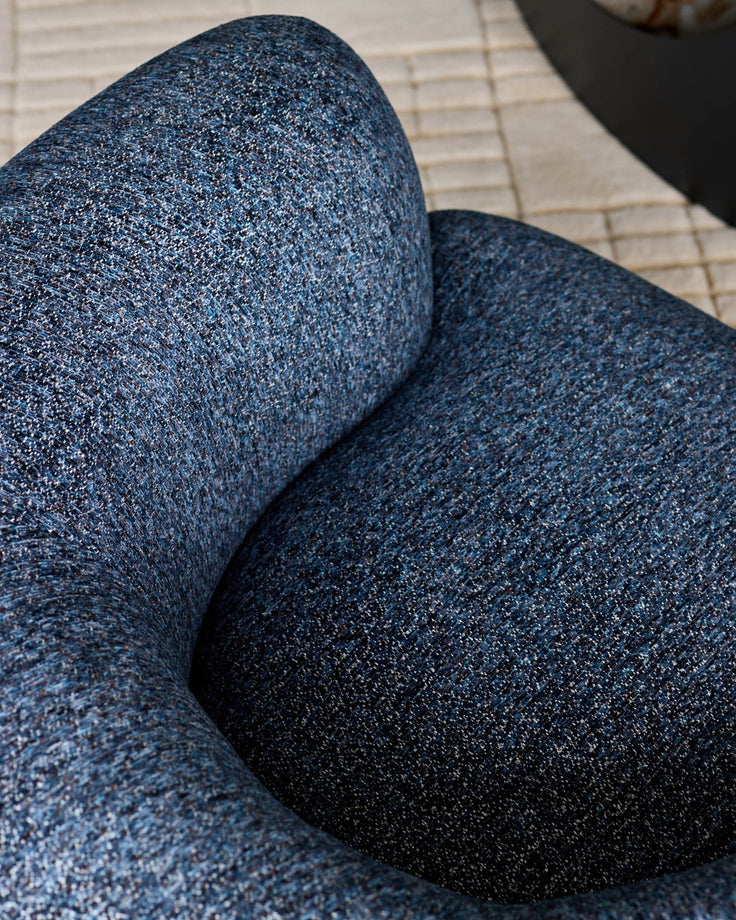 Close-up of navy weave fabric on Florence armchair, showing textured upholstery detail and curved armrest design.