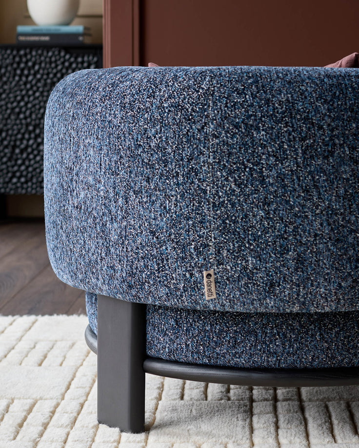 Florence armchair in navy weave fabric with dark wood legs, shown from side angle on cream rug.