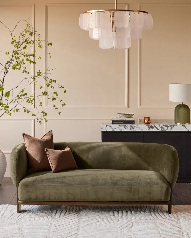Florence 2-seater sofa in olive-green fabric with dark wood base, curved design, styled in modern living room.