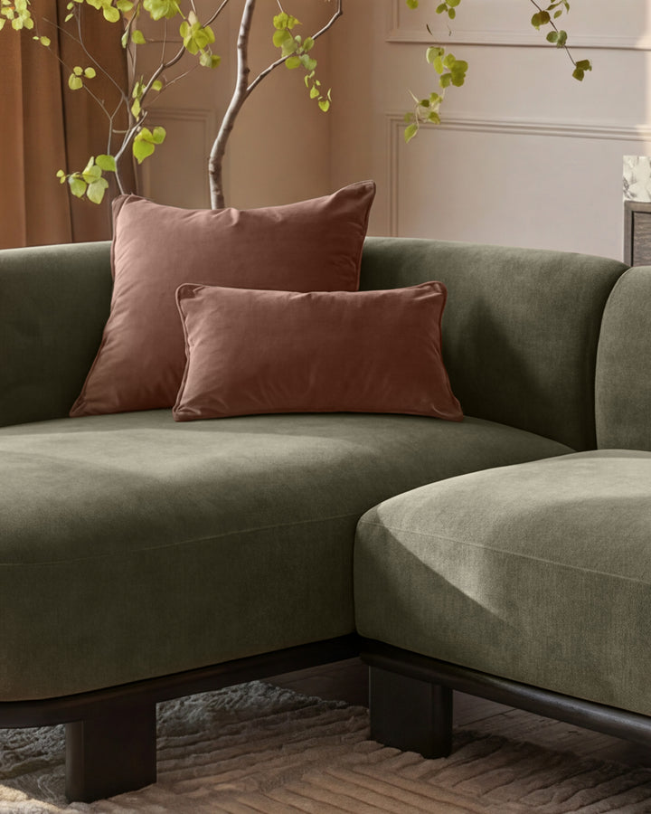 Florence left-hand facing chaise sofa in olive green fabric with burgundy pillows, dark wood base, styled with decorative branches.