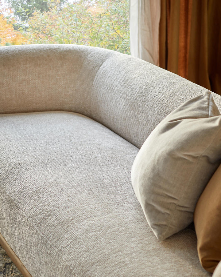 A beige sofa with scatter cushions positioned near a window, offering a neutral and calming aesthetic.