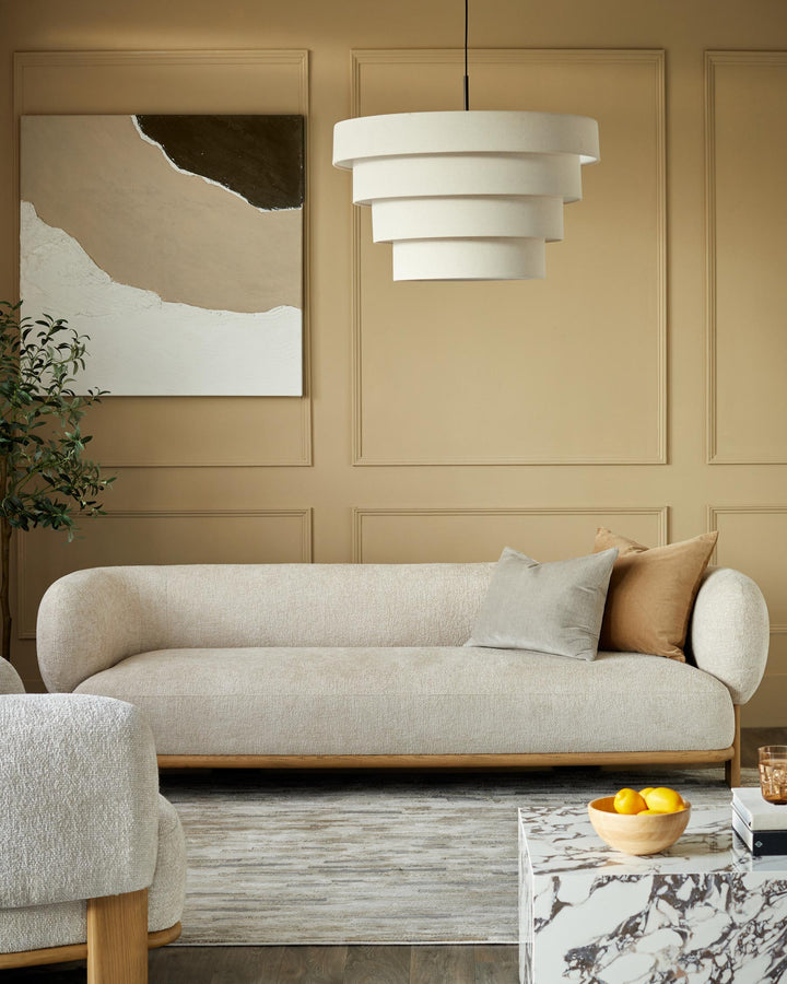 A stylish living room featuring a sofa, armchair, marble coffee table and a unique tiered lampshade.