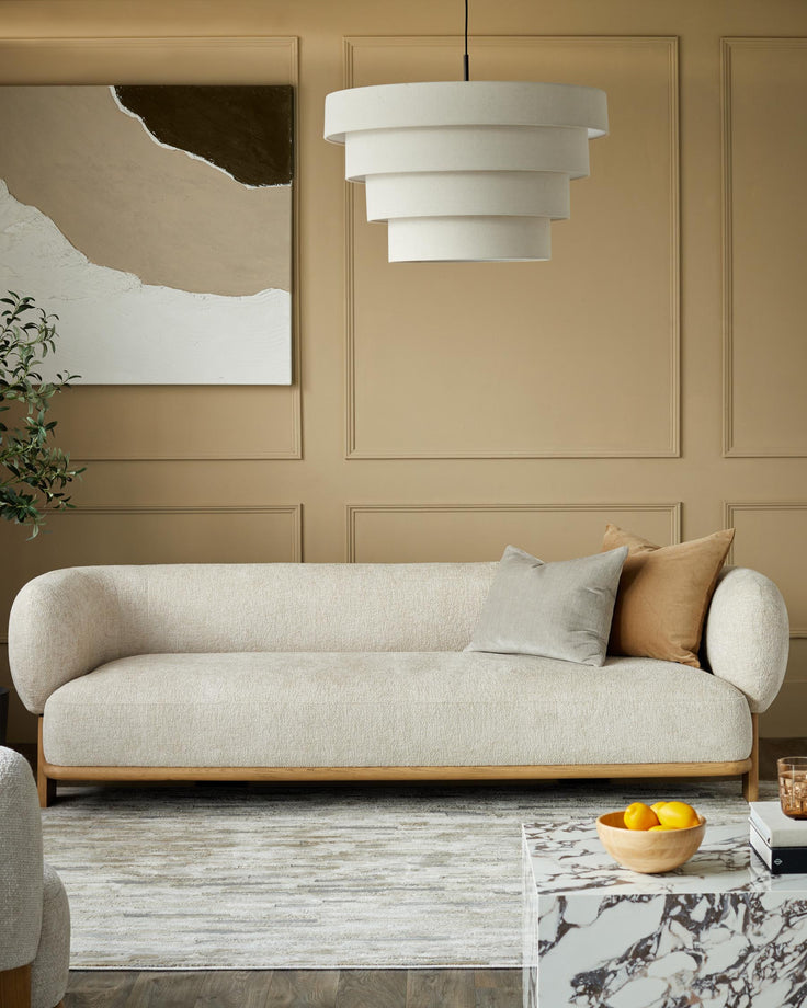 Modern living room with a neutral sofa, statement light, abstract art, and marble coffee table.