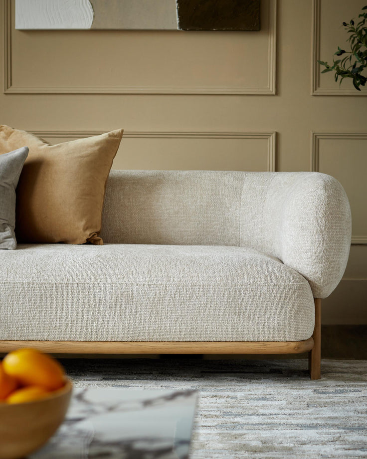 A neutral-toned sofa with decorative cushions, complemented by a wooden frame. Elegant living room furniture.