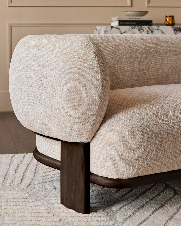 Florence 2-seater sofa with natural fabric upholstery and dark wood legs, shown from side angle highlighting curved armrest.