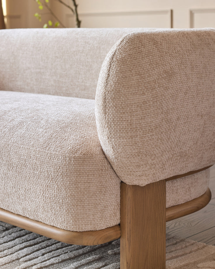 Florence 2-seater sofa close-up showing natural wood frame, rounded armrest, and beige fabric upholstery