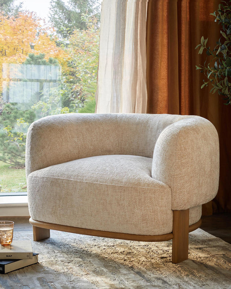 A stylish, comfy, cream armchair with a wooden base sits next to a sunlit window. Perfect for modern living rooms.