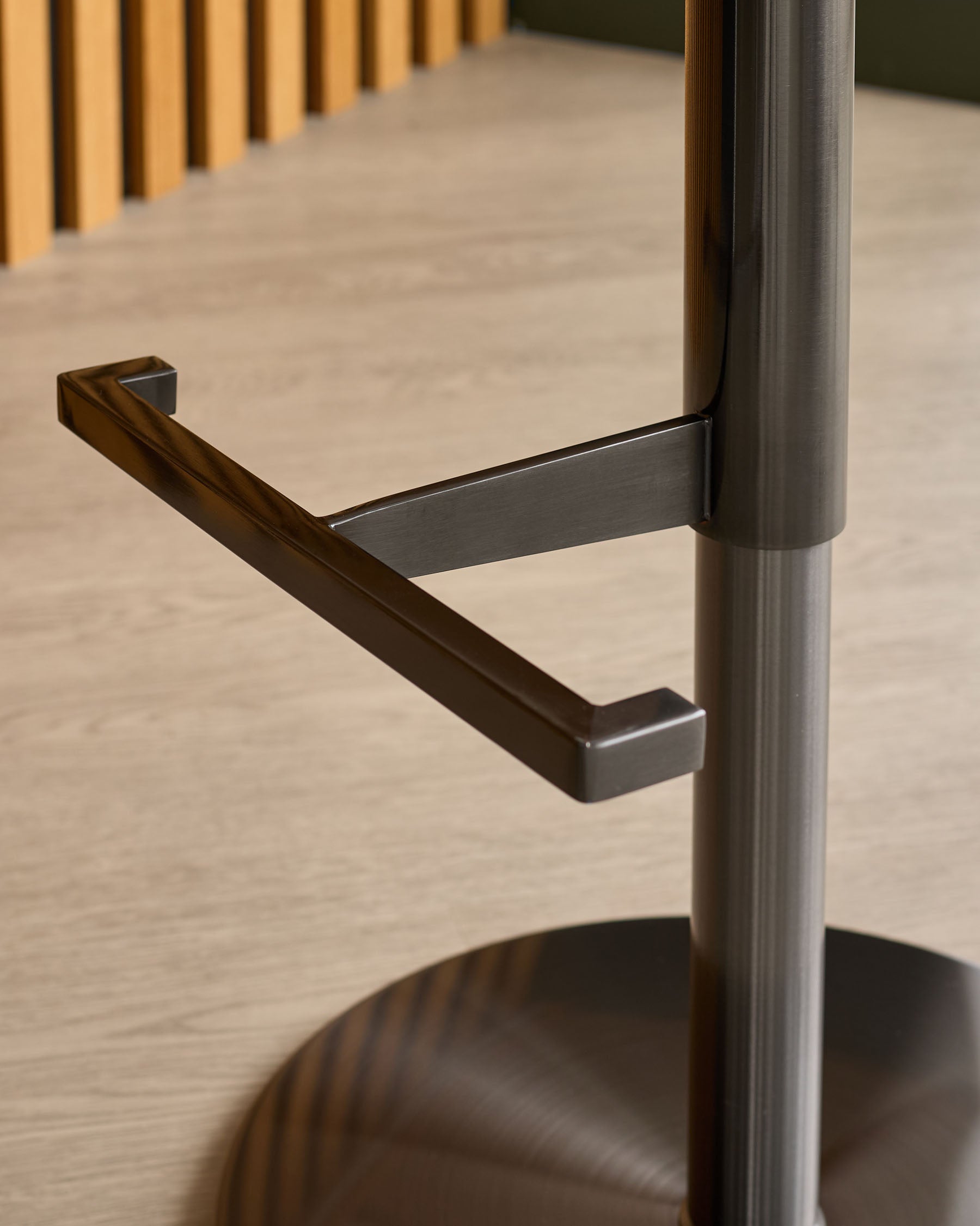 Black metal handle and pole detail of Elodie gas-lift bar stool with mocha velvet seat.