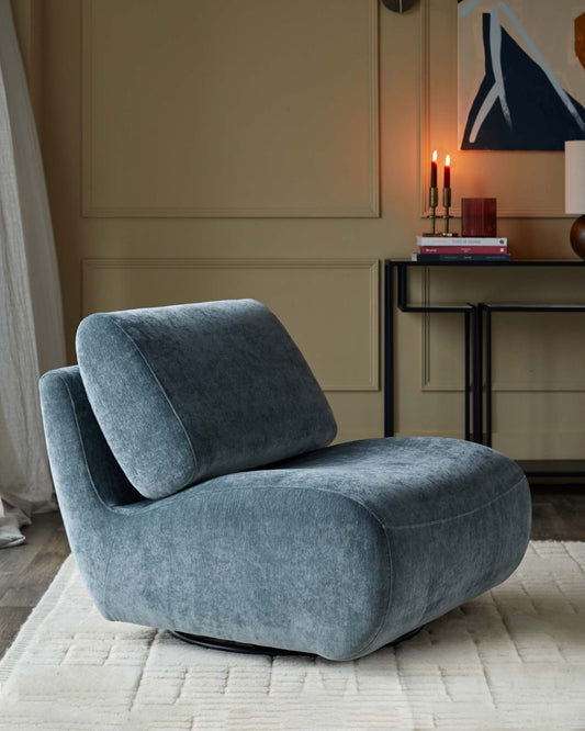 Stylish blue velvet swivel chair, positioned on a cream textured rug next to a slim console table.