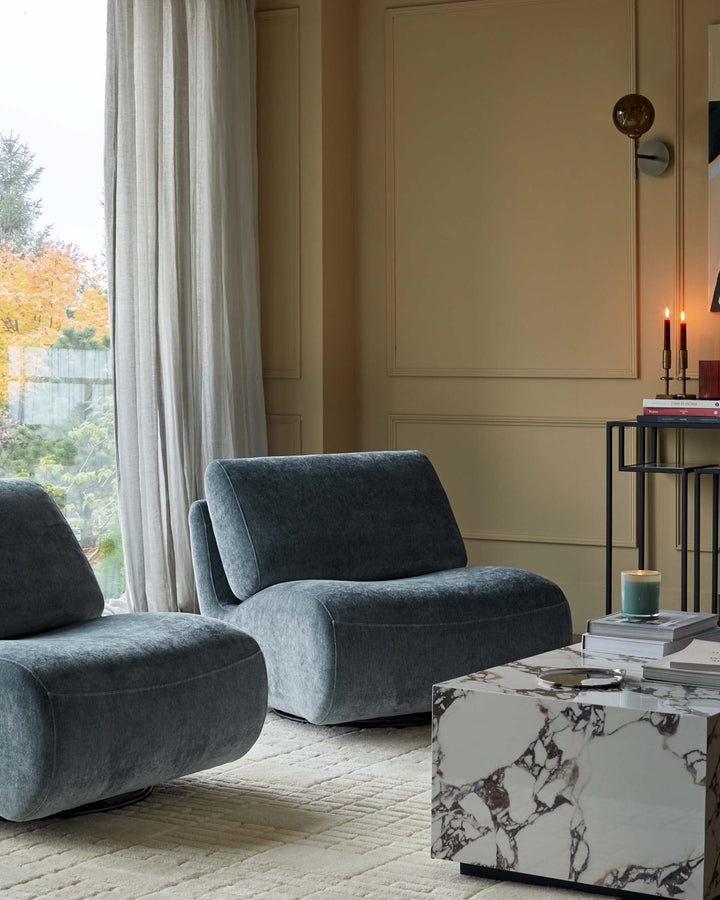 Stylish interior featuring two armchairs, a marble coffee table and side table, bathed in warm, natural light.