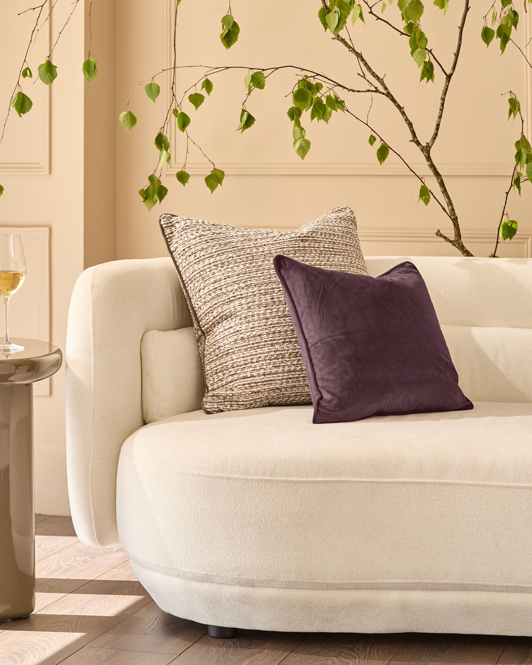 Franco cushion in large size, chocolate brown velvet, displayed on a cream armchair in a styled living room setting.