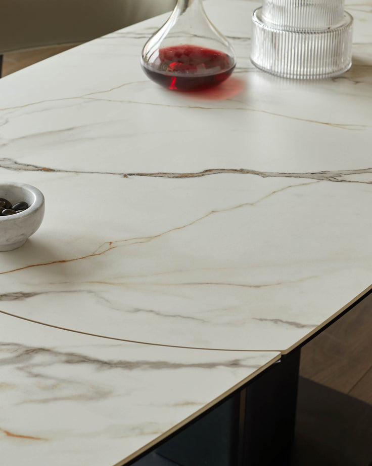 Close-up of a stylish table with a marble-effect top, featuring decorative glass and a bowl of olives.