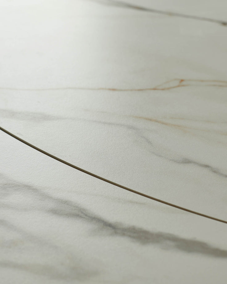 Close-up of a cream marble table surface with subtle veining and a sleek, modern edge detail.