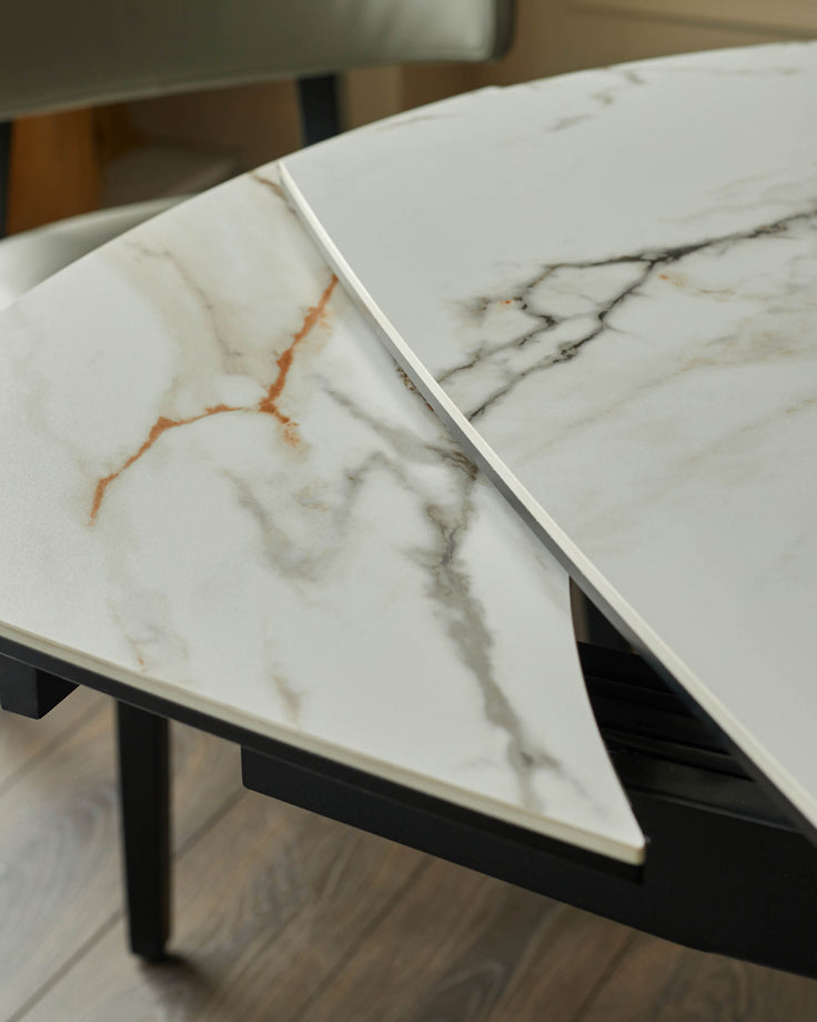Close-up of a marble effect dining table with a black frame and additional leaf.