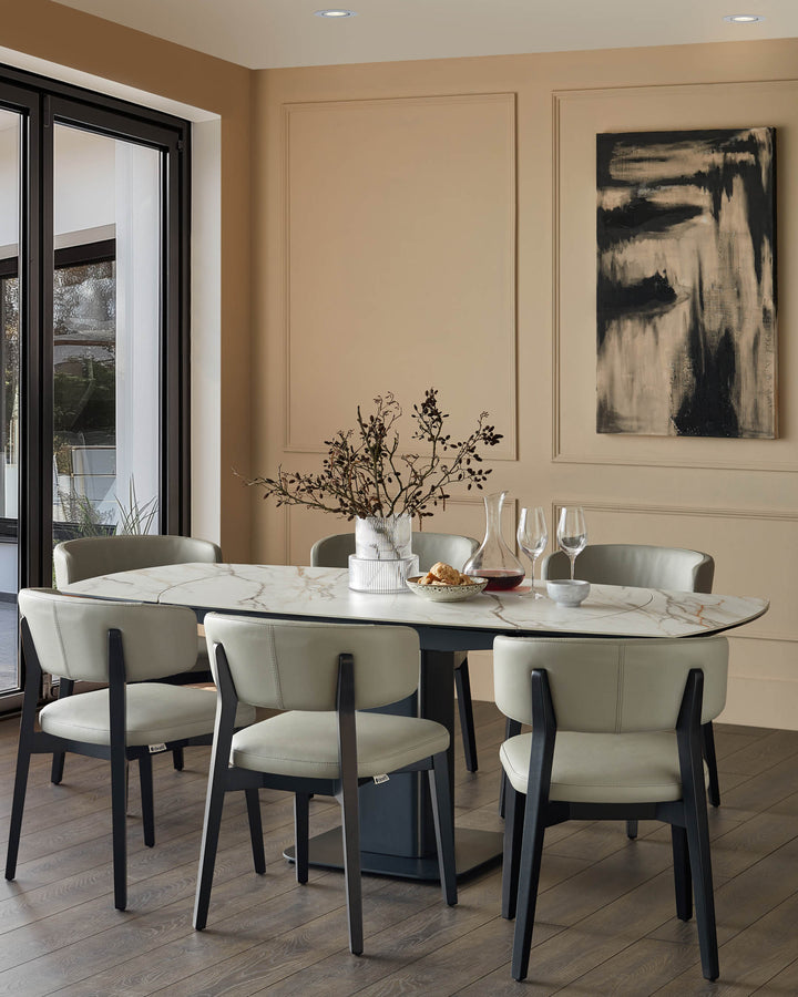 Dining room with a marble table surrounded by six chairs, plus a contemporary piece of art on the wall.
