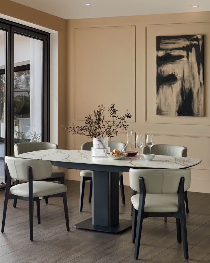 A dining table with marble-effect top and dark grey chairs with light grey leather seats. A modern dining set for the home.