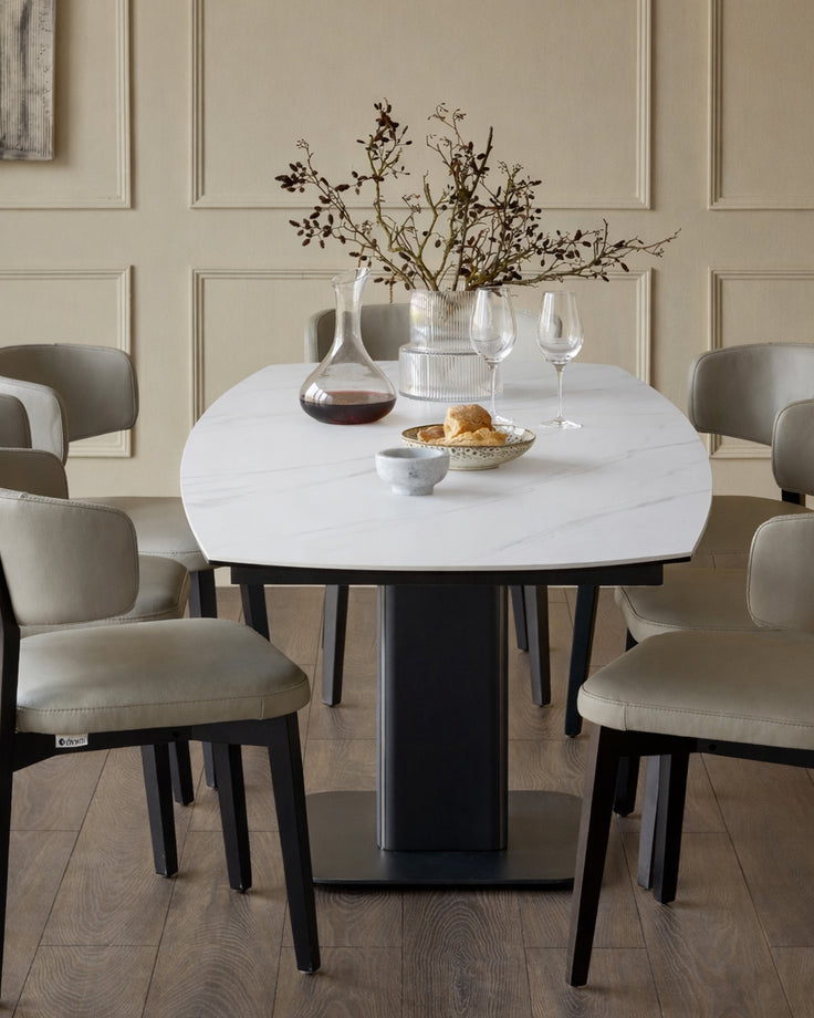 Fraser extending dining table in white ceramic with black base, surrounded by beige upholstered chairs in a modern dining room.