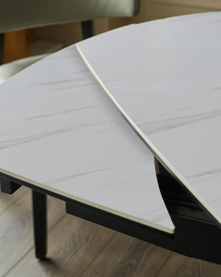 Fraser extending dining table with white ceramic top and black metal base, shown open at an angle.