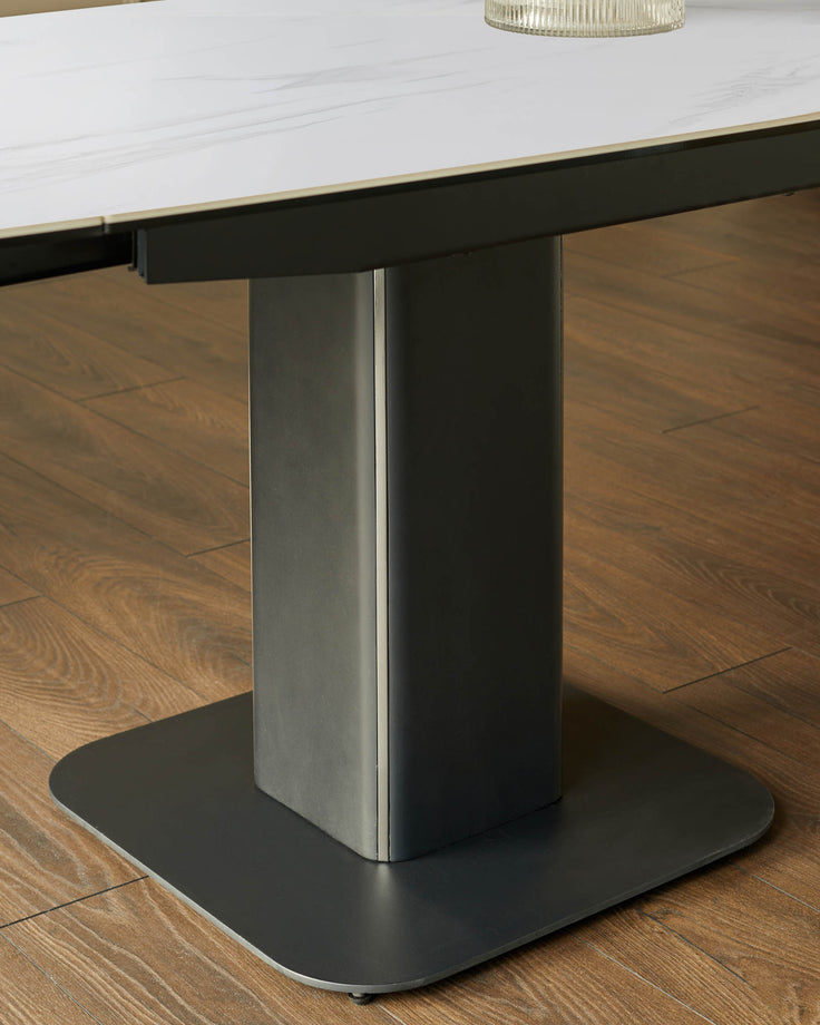 Fraser extending dining table base detail showing cylindrical pedestal with black oval foot on wooden floor.