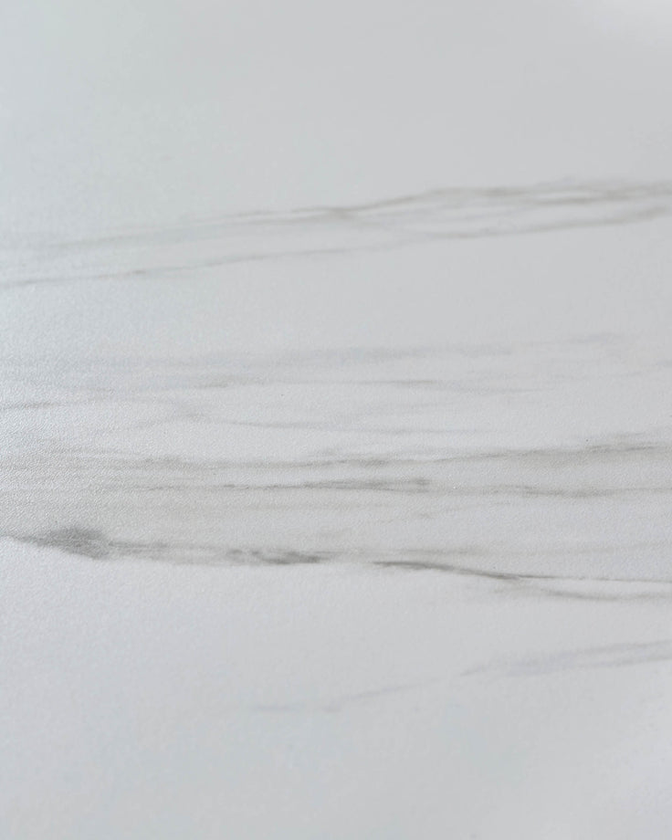 White ceramic dining table surface with wood grain texture detail, close-up view of tabletop finish.