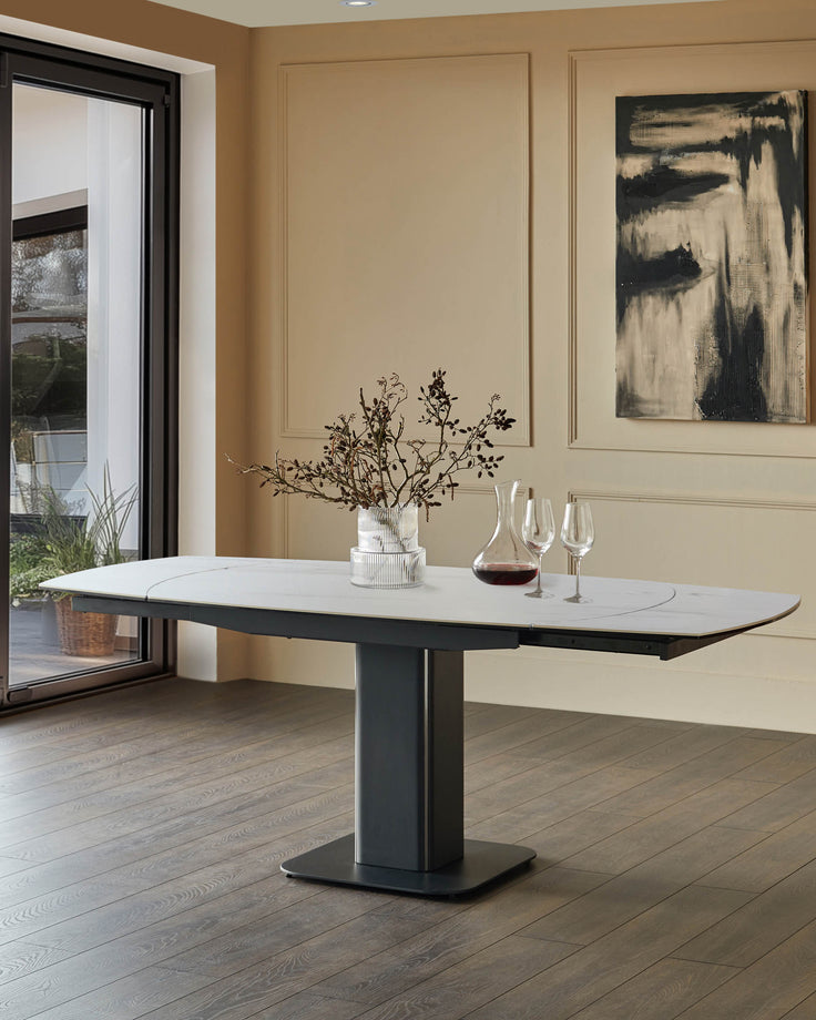 Fraser extending dining table in white ceramic with dark base, shown extended in a modern dining room setting.